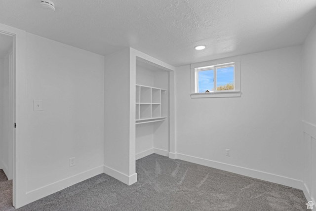 unfurnished bedroom featuring carpet floors, a textured ceiling, and baseboards