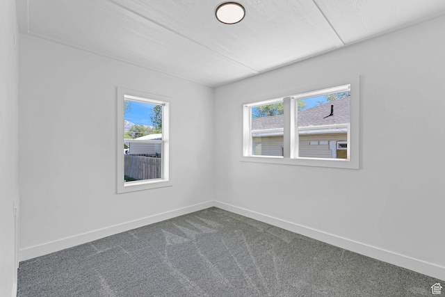 empty room featuring healthy amount of natural light, carpet flooring, and baseboards