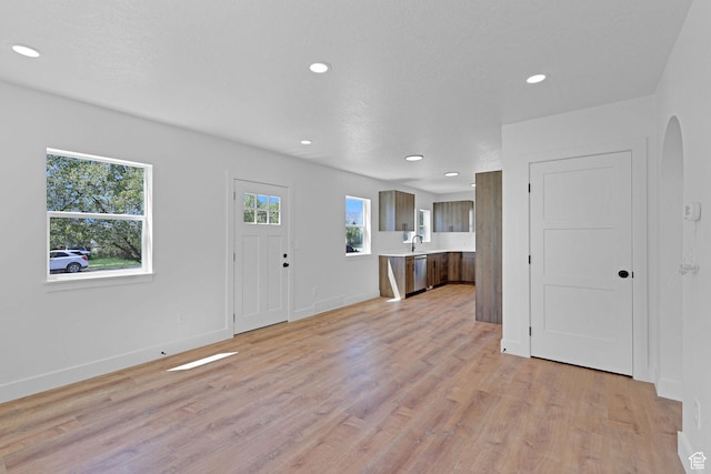 entryway with arched walkways, light wood finished floors, recessed lighting, and baseboards