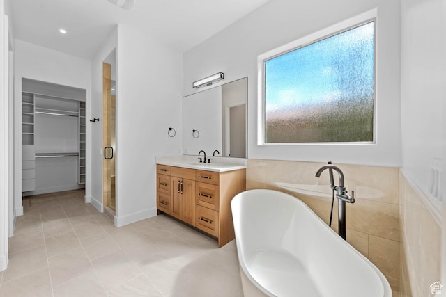 bathroom with a stall shower, a spacious closet, vanity, and a freestanding tub