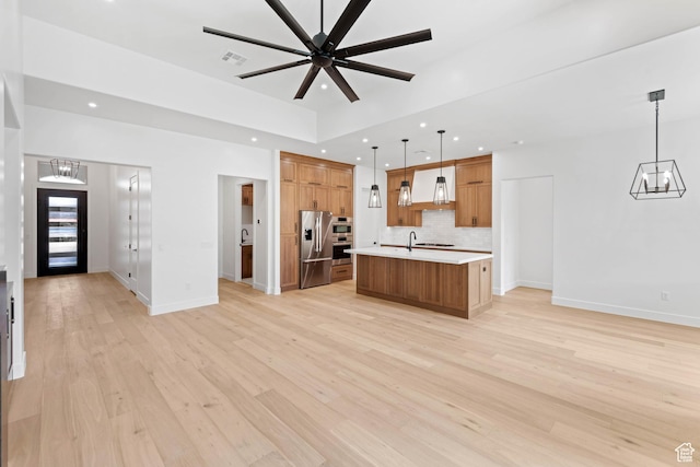 kitchen with stainless steel fridge, open floor plan, premium range hood, light countertops, and a chandelier