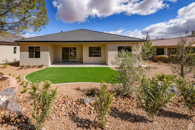 back of property with stucco siding, a yard, and a patio area