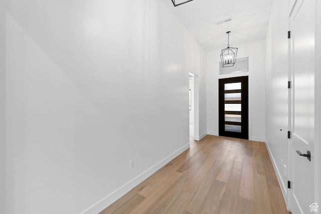 foyer entrance featuring light wood-style floors, baseboards, and a chandelier