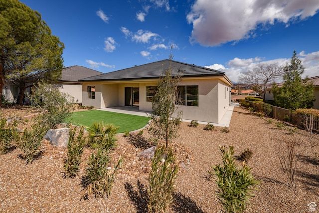 rear view of house with stucco siding and a patio