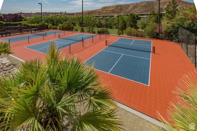 view of tennis court with fence, community basketball court, and a mountain view