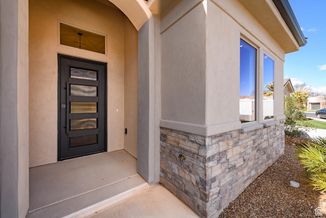 doorway to property with stone siding and stucco siding