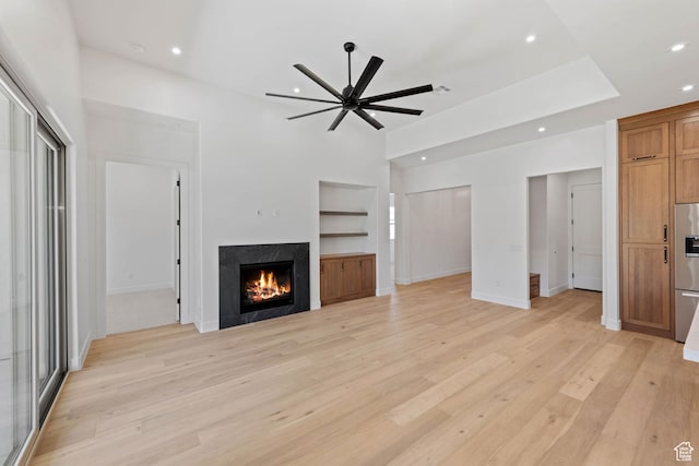 unfurnished living room featuring recessed lighting, a ceiling fan, light wood-style flooring, built in features, and a premium fireplace
