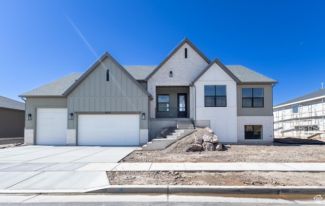 3573 W 725 S Unit 106, West Weber, UT 84401 - view of front of property featuring brick siding, an attached garage, driveway, board and batten siding, and roof with shingles