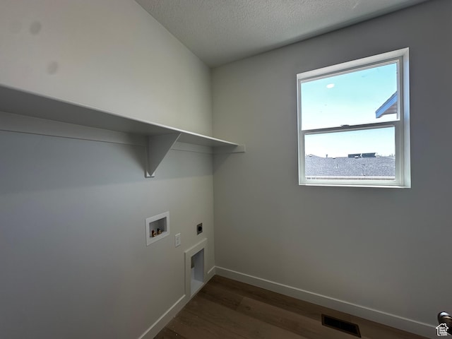 washroom featuring electric dryer hookup, washer hookup, dark wood-type flooring, baseboards, and a textured ceiling