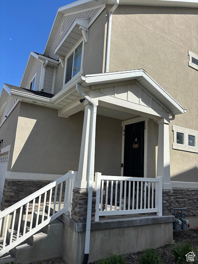 4317 W Quiet Shade Dr, Herriman, UT 84096 - view of side of property with stone siding, stucco siding, a porch, and a garage