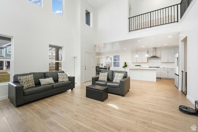 living area featuring a high ceiling, light wood-style flooring, plenty of natural light, and baseboards