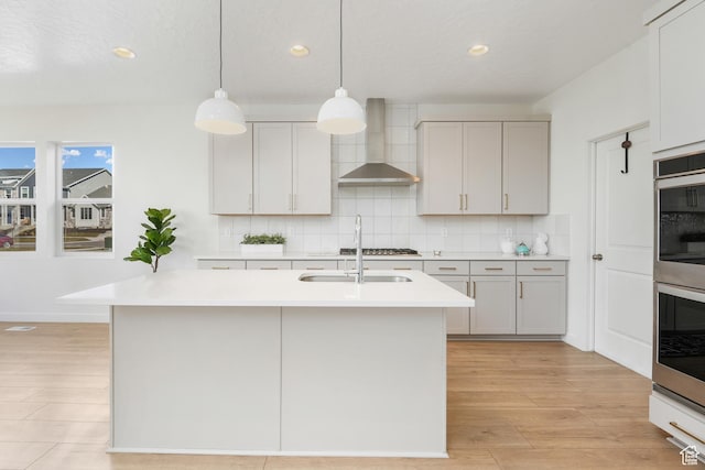 kitchen featuring wall chimney exhaust hood, recessed lighting, light wood finished floors, light countertops, and tasteful backsplash