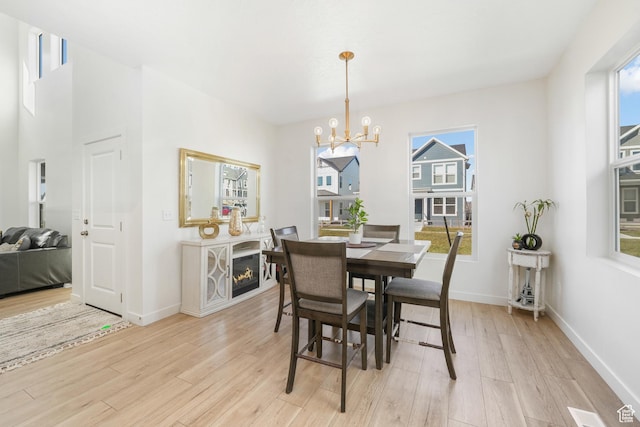 dining room with a chandelier, healthy amount of natural light, light wood-type flooring, and baseboards