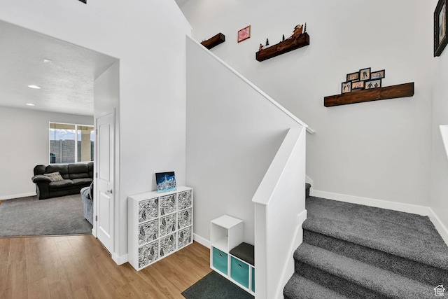 staircase featuring wood finished floors, baseboards, and recessed lighting