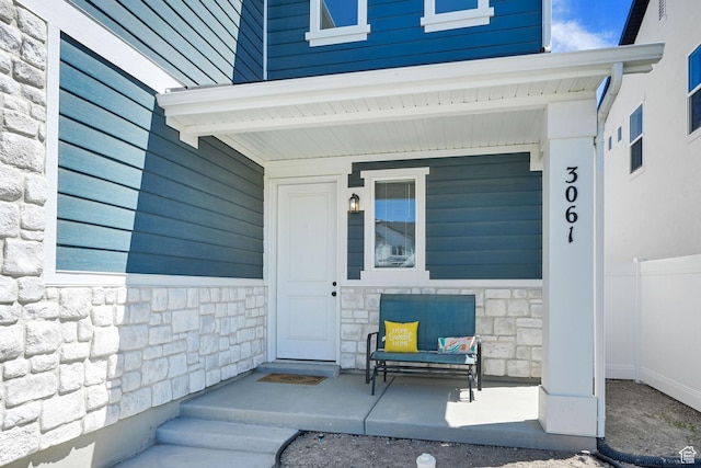 doorway to property with stone siding and covered porch