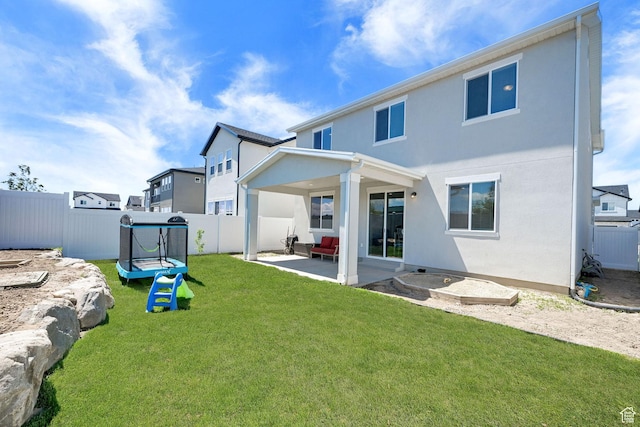 back of house featuring a trampoline, a patio, and stucco siding