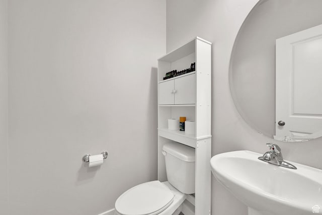 half bathroom with a sink, toilet, and baseboards