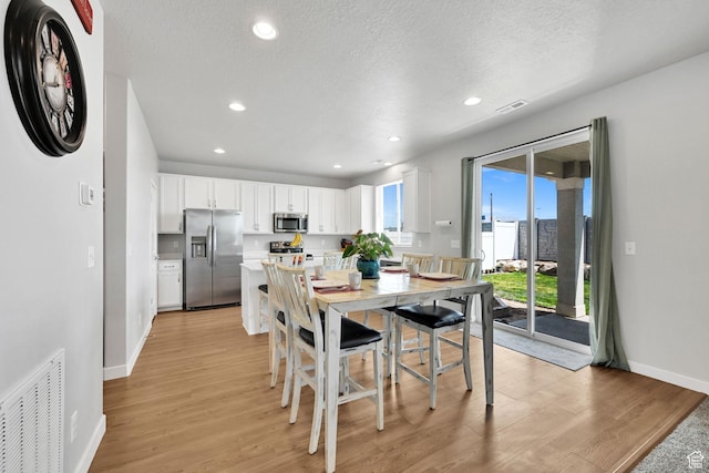 dining space with baseboards, light wood-style flooring, recessed lighting, and a textured ceiling