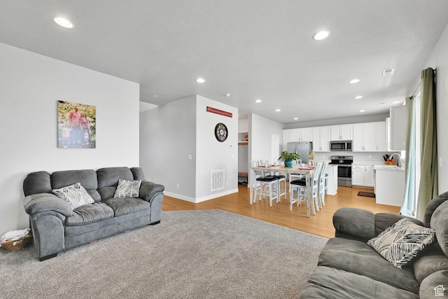 living area featuring recessed lighting, light wood-type flooring, and baseboards