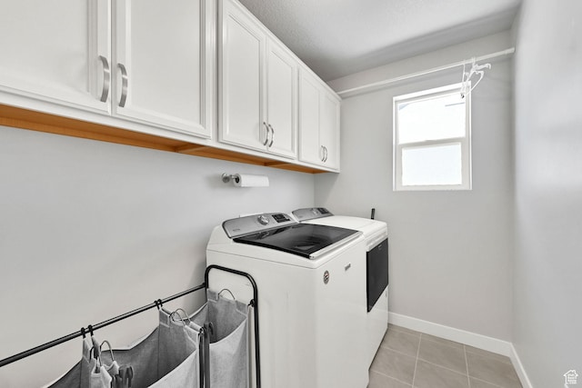 clothes washing area featuring independent washer and dryer, cabinet space, baseboards, and light tile patterned floors