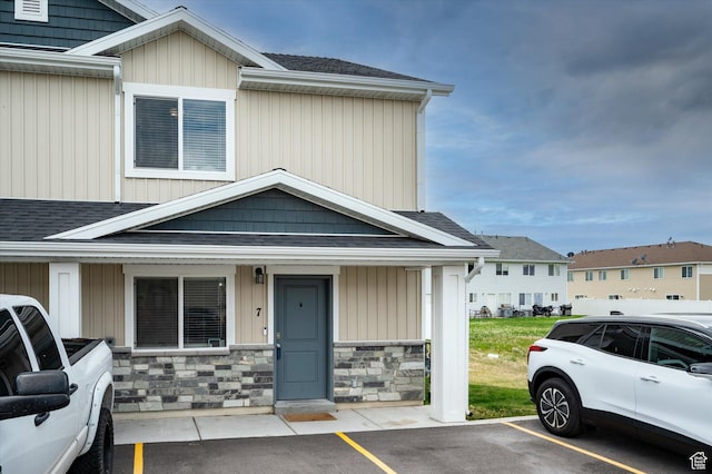 2460 W 450 N Unit 7, Tremonton, UT 84337 - view of front of property featuring a shingled roof, uncovered parking, stone siding, and covered porch