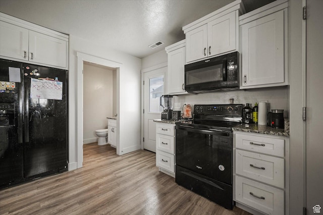 2460 W 450 N Unit 7, Tremonton, UT 84337 - kitchen with black appliances, light wood-style flooring, white cabinets, dark stone countertops, and baseboards