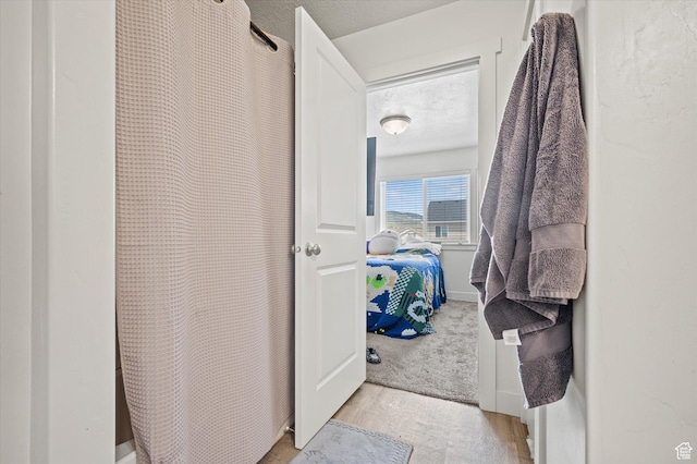 2460 W 450 N Unit 7, Tremonton, UT 84337 - ensuite bathroom with curtained shower, a textured ceiling, and wood finished floors