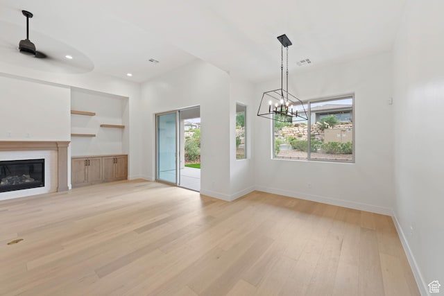 unfurnished living room with a chandelier, light wood-style flooring, baseboards, a glass covered fireplace, and recessed lighting