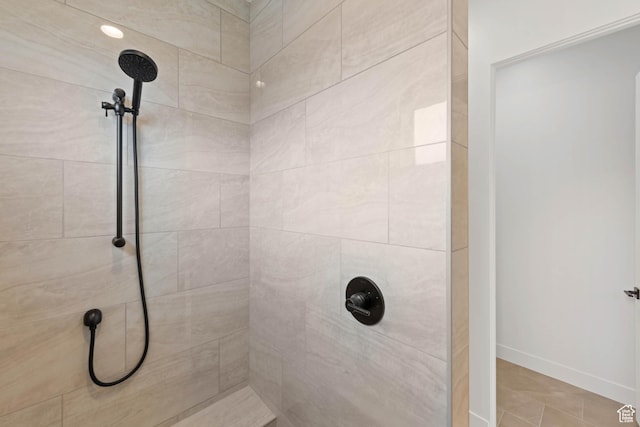 full bath featuring tiled shower and baseboards