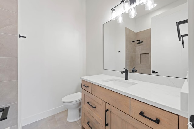 bathroom with a tile shower, toilet, vanity, tile patterned flooring, and baseboards