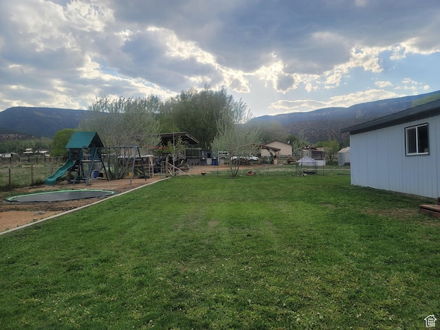 view of green lawn with a playground and a mountain view