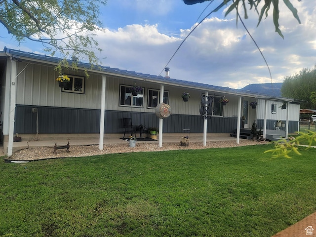 back of house featuring a lawn and covered porch