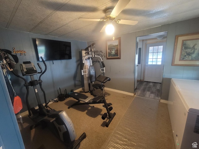 workout room featuring ceiling fan, a textured ceiling, carpet flooring, and baseboards