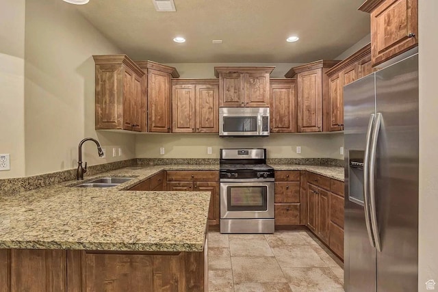 5198 N University Ave Unit 105, Provo, UT 84604 - kitchen featuring appliances with stainless steel finishes, a sink, a peninsula, light stone counters, and brown cabinets