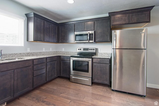 4129 W Miner Vw, Herriman, UT 84096 - kitchen with stainless steel appliances, wood finished floors, a sink, dark brown cabinets, and recessed lighting