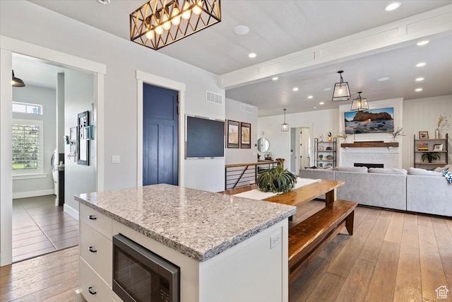 5707 Scenic Ln, Mountain Green, UT 84050 - kitchen featuring stainless steel microwave, light wood-type flooring, white cabinets, recessed lighting, and light stone countertops