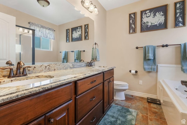 full bath featuring baseboards, toilet, double vanity, a tub to relax in, and stone finish floors