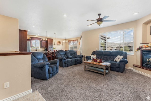 carpeted living area with a ceiling fan, a glass covered fireplace, plenty of natural light, recessed lighting, and baseboards