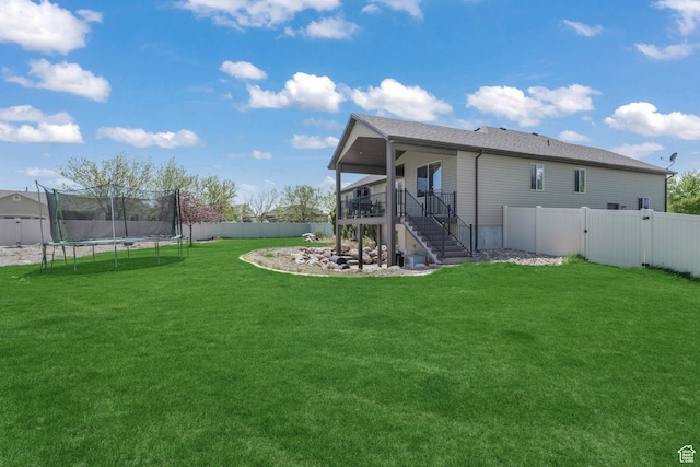 rear view of property featuring a trampoline, stairway, a gate, and a wooden deck