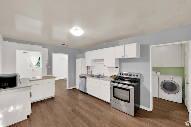 kitchen featuring appliances with stainless steel finishes, a sink, independent washer and dryer, and dark wood finished floors