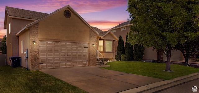 view of front of house with concrete driveway, stucco siding, an attached garage, a front yard, and stone siding