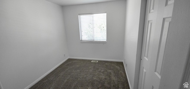 empty room with dark carpet and baseboards