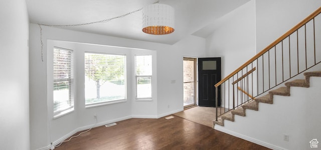 entrance foyer featuring wood finished floors, baseboards, stairway, and vaulted ceiling