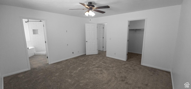 unfurnished bedroom with carpet, a walk in closet, ensuite bathroom, a closet, and baseboards