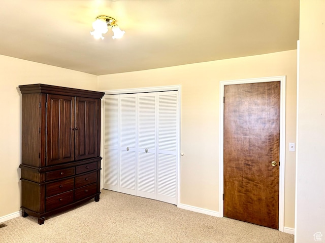 unfurnished bedroom featuring light carpet, baseboards, and a closet