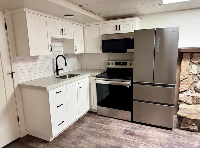 kitchen with appliances with stainless steel finishes, a sink, white cabinets, light countertops, and dark wood-style flooring