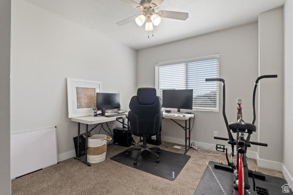 carpeted home office featuring a ceiling fan and baseboards