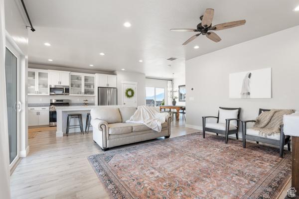 living room featuring light wood finished floors, recessed lighting, ceiling fan, and baseboards