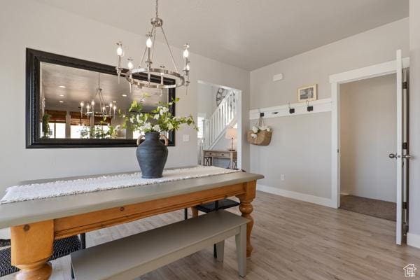 dining area featuring a chandelier, wood finished floors, stairs, and baseboards