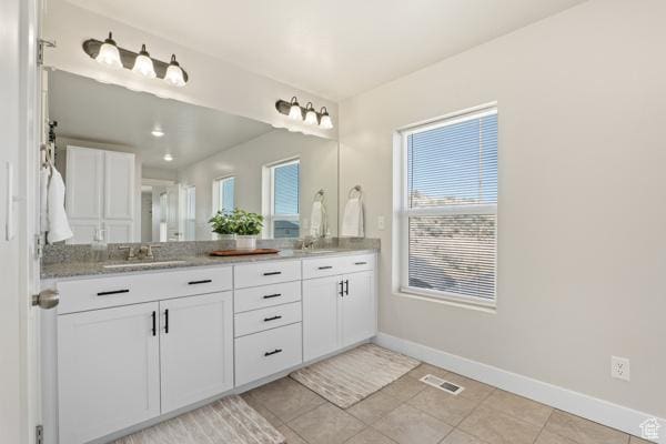 bathroom with baseboards, double vanity, and tile patterned flooring